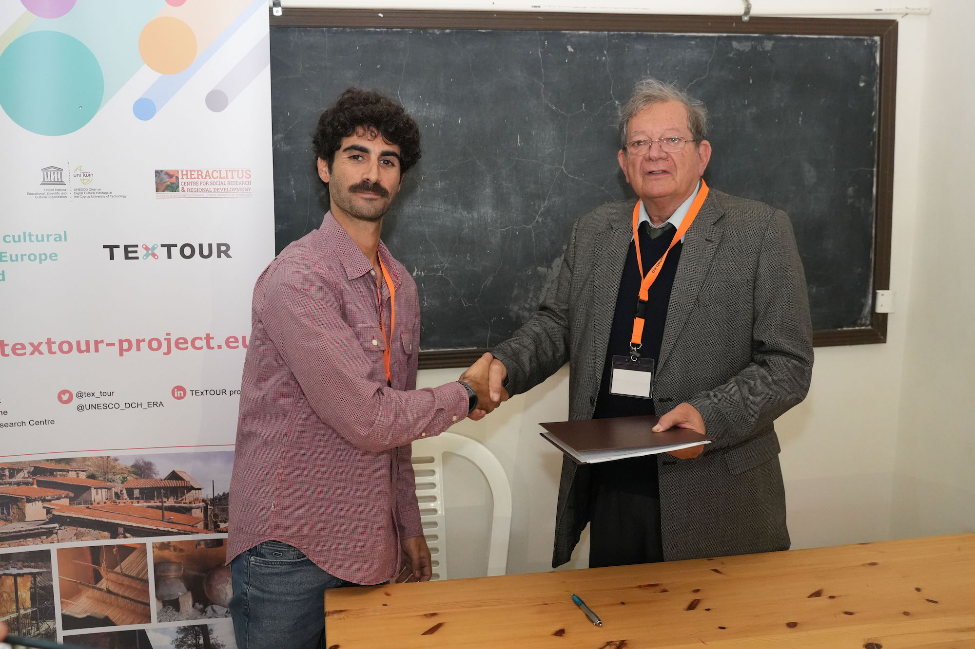 A representative of the Municipality of Anfeh and a representative of the Council of Fikardou share hands after signing of the memorandum of Understanding
